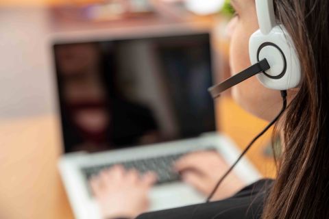 Women with headset on, working on a laptop