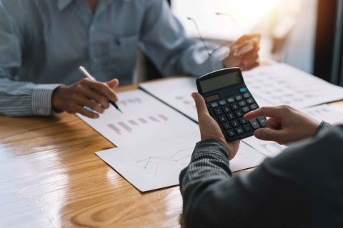 Businessman pointing at a graph with a pen, another using a calcuator