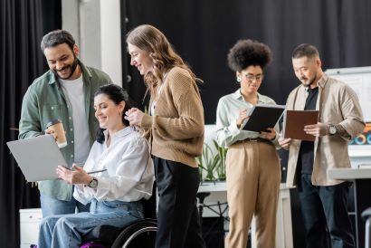 A woman in a wheelchair discussing a project on her laptop with colleagues