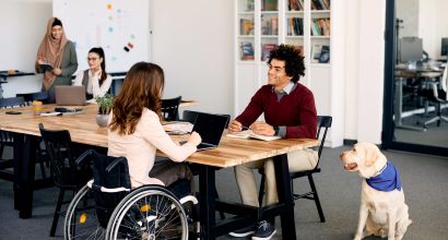 Happy black businessman colleague with disability talking while working at pet friendly office. Photos - Envato Elements